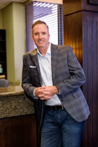 Dr. Scott Dooley, dentist in Garland TX, radiating warmth and professionalism with a friendly smile in his office.